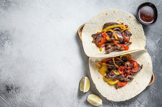 Foto fajitas met rundvleesreepjes, gekleurde paprika en uien, geserveerd met tortilla's en salsa