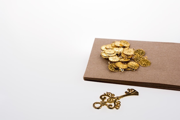 Ключ и коробка поддельных золотых монет на белом фоне