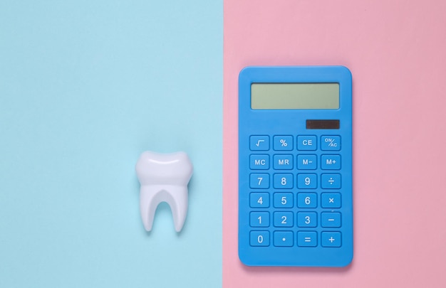 Fake tooth on blue pink background. Dental treatment costs. Top view