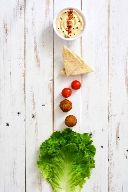 Falafel ball with hummus on white wooden table