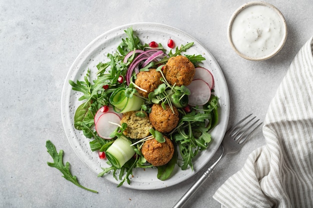 Falafel en verse groentesalade op een witte ceramische plaat op concrete hoogste mening als achtergrond