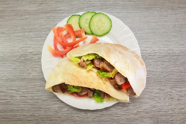 Falafel and fresh vegetables in pita bread on wooden table