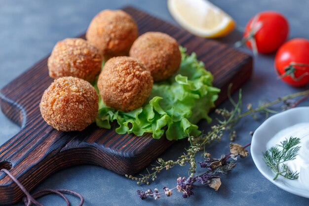 Falafel lies on a wooden cutting board. 