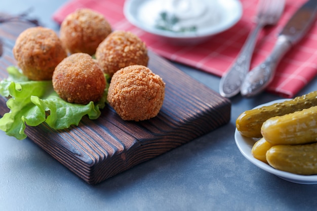 Falafel lies on a wooden cutting board. 