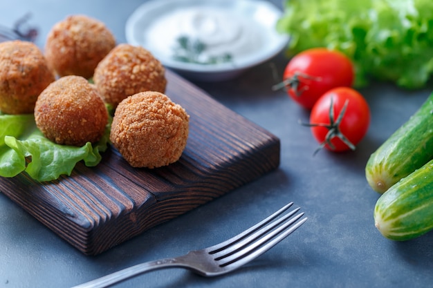 Falafel lies on a wooden cutting board. 