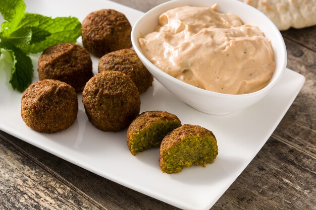 Falafel on a plate and tahini sauce on wooden table