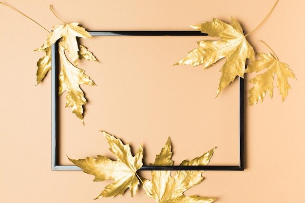 Photo fall and autumn flat lay with painted matallic golden leaves creative on beige background copy space