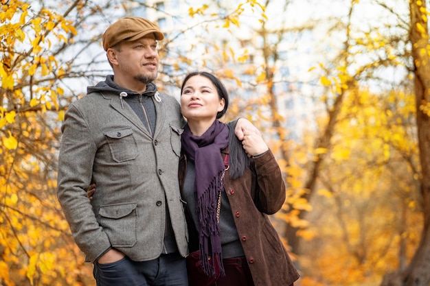 Fall caucasian pair is walking through the fall forest casual couple walks under leaf fall in octobe...