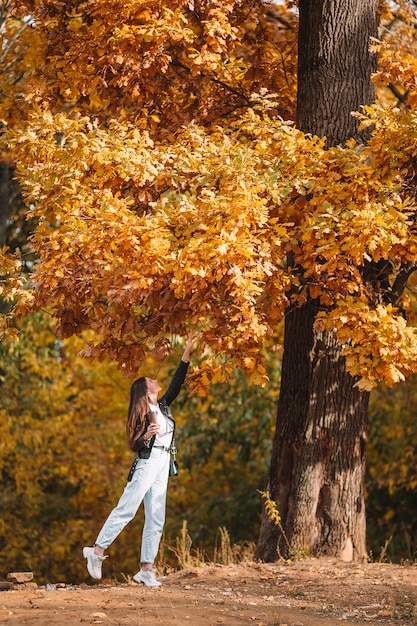 Fall concept - beautiful woman in autumn park under fall foliage