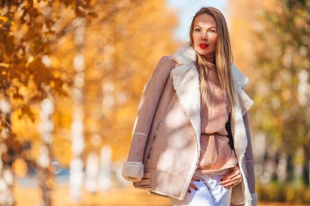 Concetto di caduta - bella donna nella sosta di autunno sotto il fogliame di caduta