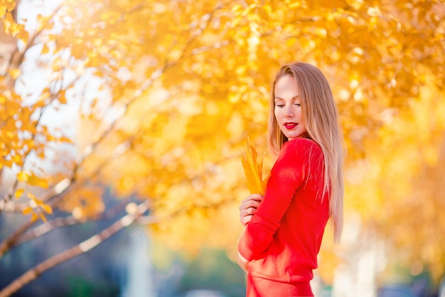 秋のコンセプト - 秋の紅葉の下で秋の公園でコーヒーを飲みながら美しい女性