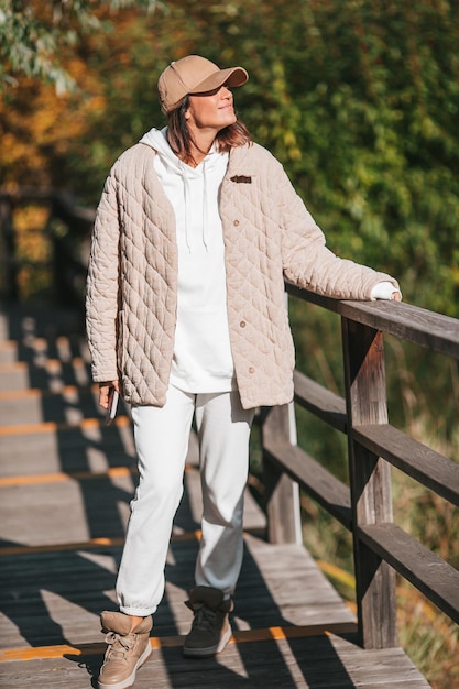 秋の概念紅葉の下で秋の公園でコーヒーを飲む美しい女性