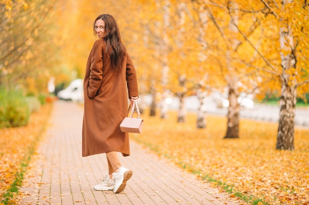 写真 秋のコンセプト-秋の紅葉の下で秋の公園でコーヒーを飲みながら美しい女性