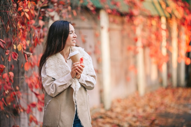 Fall concept - mooie vrouw koffie drinken in de herfst park onder bladeren vallen