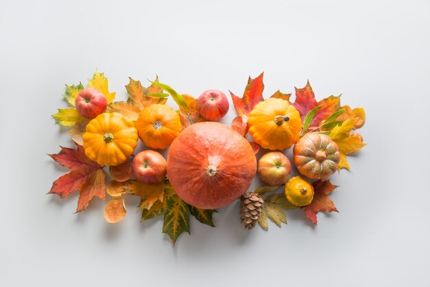 Fall decor for Thanksgiving Day with pumpkins, leaves, apples on grey.