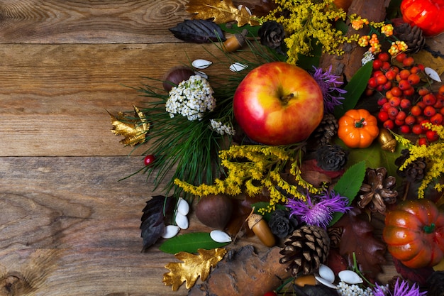 Fall decoration with flowers and apple on wooden table