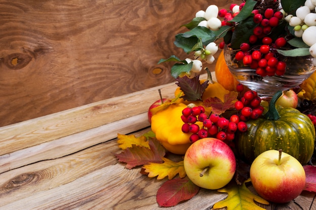 Photo fall enterpiece with rowan berries, green pumpkin, oak leaves and apples, copy space