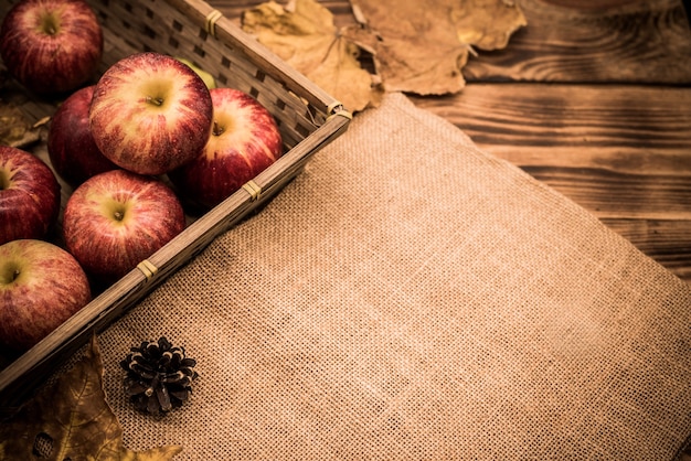 Fall harvest cornucopia. Red apples in the garden. Copy space on wood background in Autumn season.