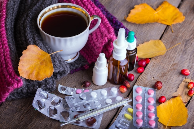 Fall and health care. home pharmacy - cup of tea, pills and thermometer on a wooden background