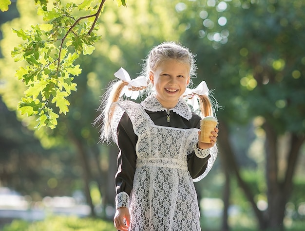 In the fall in the park, a girl in a school uniform with ice cream in her hands