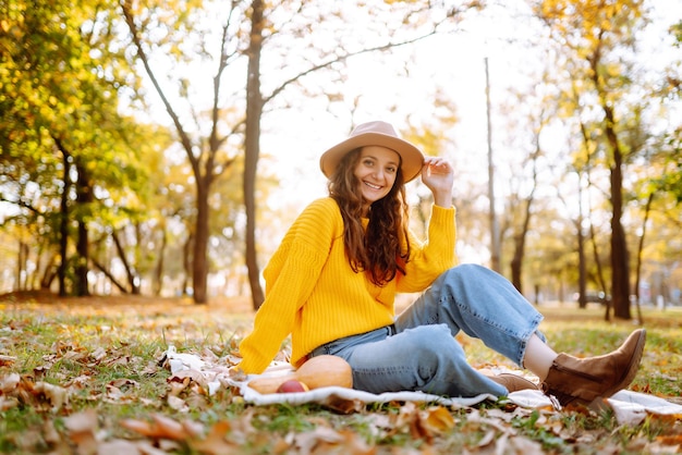 Fall picnic with pumpkin Stylish woman enjoying autumn weather in the park Autumn harvest