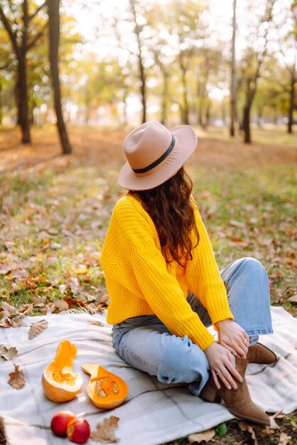 Fall picnic with pumpkin Stylish woman enjoying autumn weather in the park Autumn harvest