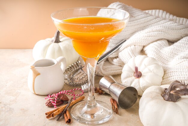 Bevande autunnali e invernali. ringraziamento e cocktail di halloween. torta di zucca margarita o martini con stecca di cannella, su tavola di pietra nera. casa accogliente, con foglie autunnali, plaid, zucca, copia spazio