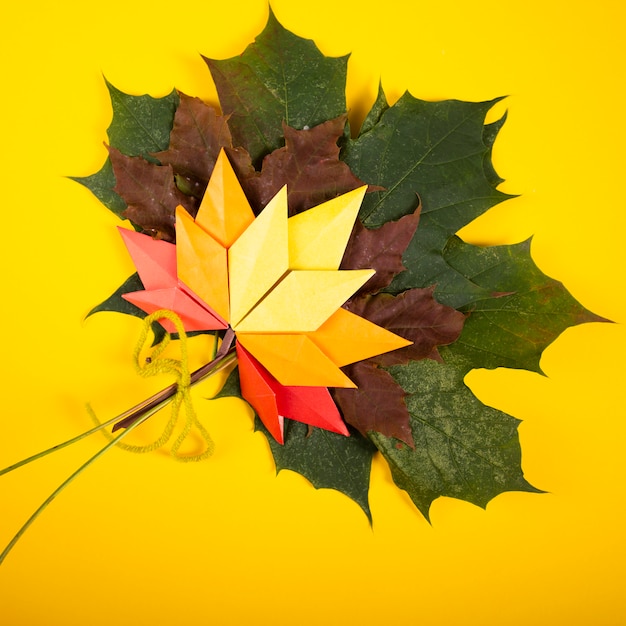 Fallen handmade leaves autumn concept traditional paper craft art origami topshot on yellow background