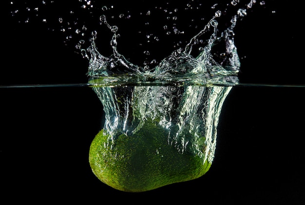 Falling avocados into the water, spray for design, freezing in motion. Water splash and vegetables