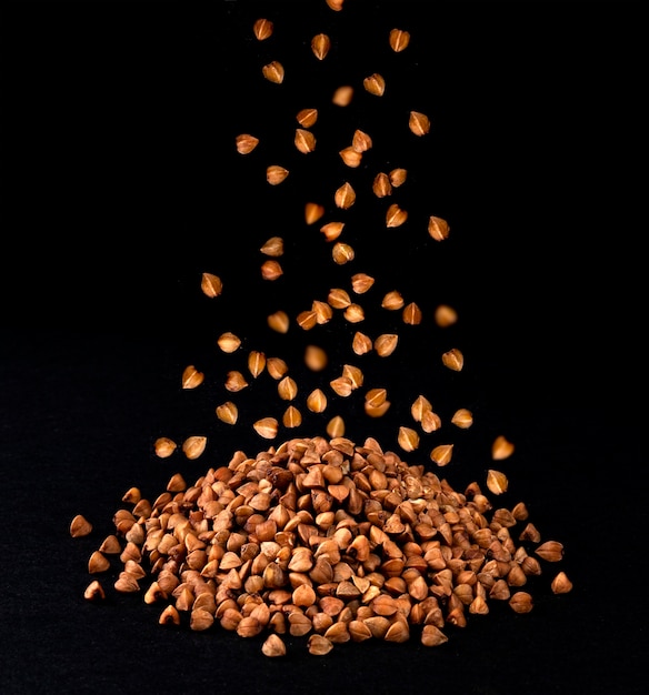 Falling buckwheat grains isolated on black