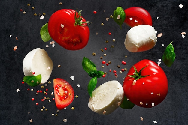 Falling caprese salad ingredients on dark background Italian appetizer