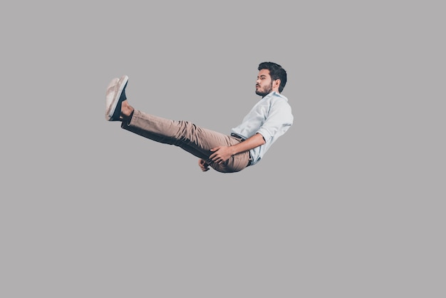 Falling down. Mid-air shot of handsome young man falling against grey background