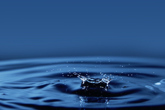 Falling drop of water closeup on a dark blue background