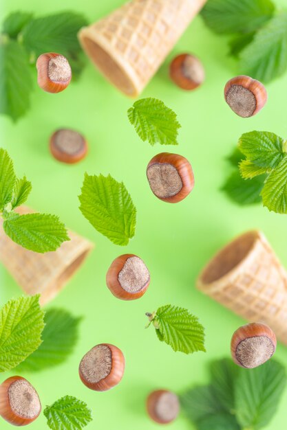 Falling hazelnuts with green leaves and wafer cups for ice cream , selective focus. Top view, flat lay