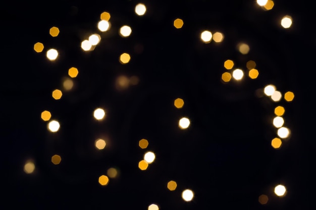 Falling hexagonal bokeh lights on black. Holiday concept.