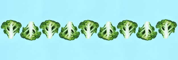 Photo falling many soaring green broccoli slices in a row on a blue background