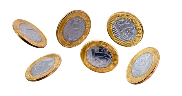 Falling one brazilian real coins isolated on white surface.