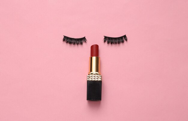 False eyelashes and lipstick on a pink background Beauty concept