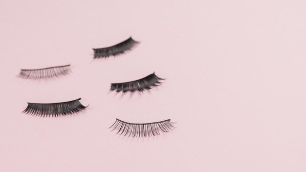 False eyelashes scattered on a pink background