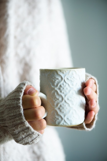 Famale handen met een gezellige keramische handgemaakte mok met koffie. Winter en Kerstmis thuis tijd concept.