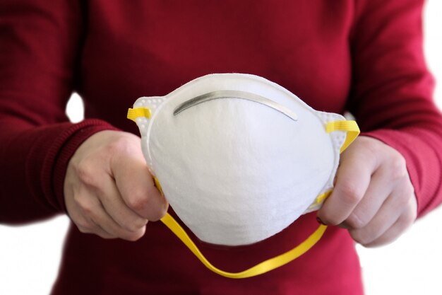 Famale hands holding white protective mask isolated on white.