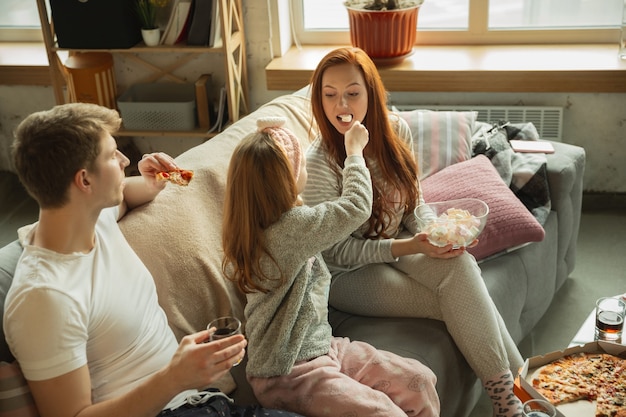 Familie brengt leuke tijd samen thuis door, ziet er gelukkig en vrolijk uit, pizza aan het eten