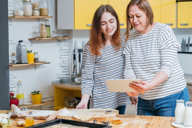 Familie culinaire hobby Moeder en dochter gebruiken tablet om koekjesrecept te zoeken