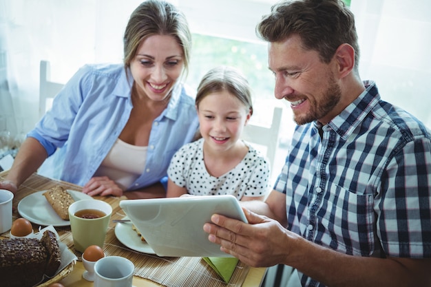 Familie die digitale tablet gebruikt terwijl ontbijt