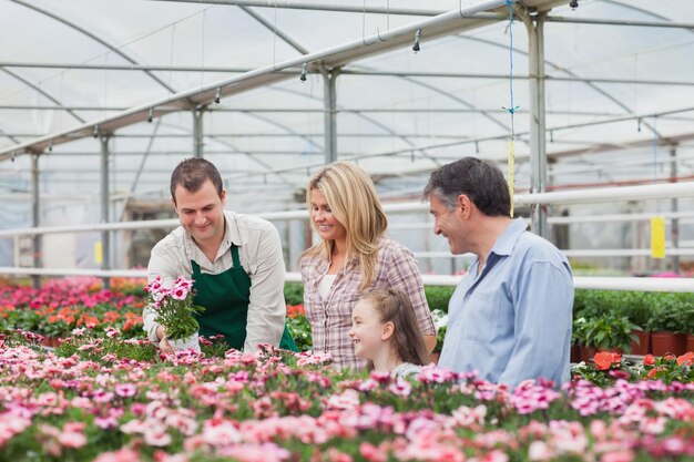 Familie die een bloem met werknemer in tuincentrum kiest