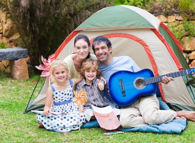 Familie die een gitaar in een tent speelt