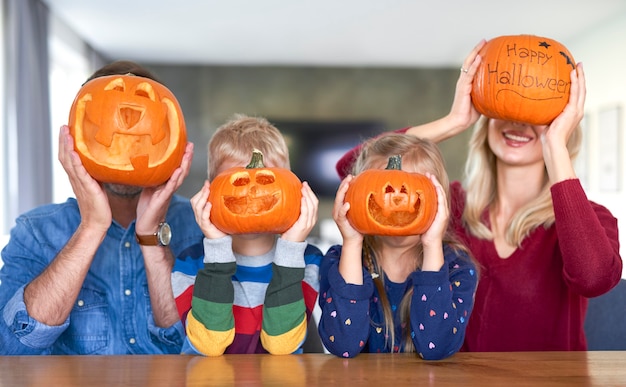 Familie die halloween-pompoenen voor hun gezicht houdt