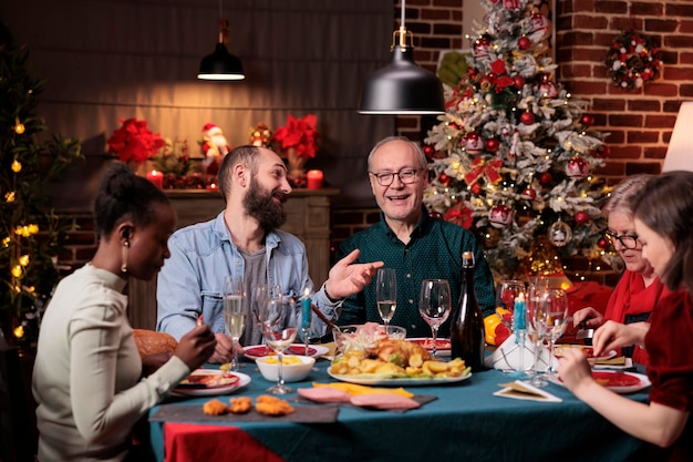 Familie die kerst samen viert, traditionele maaltijd eet, geniet van gerechten aan een feestelijke eettafel. Kerstviering op een prachtig ingerichte plek met warm kaarslicht