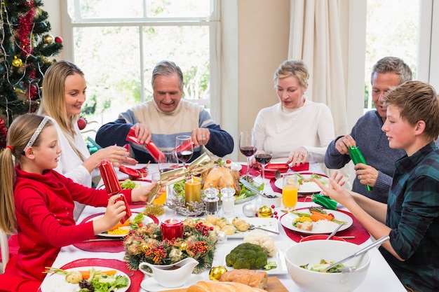 Familie die Kerstmiscrackers trekt bij de dinerlijst