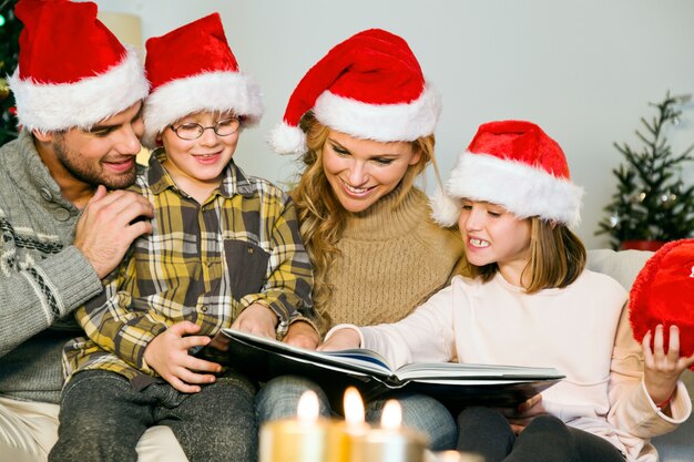 Familie die lacht met de kerstman hoeden en te kijken naar een foto album